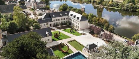 A courtyard with a swimming pool, surrounded by buildings and a river.