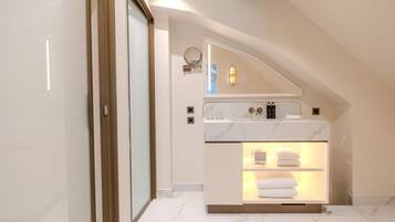 A modern bathroom with a marble countertop, a built-in shower, and a towel rack.
