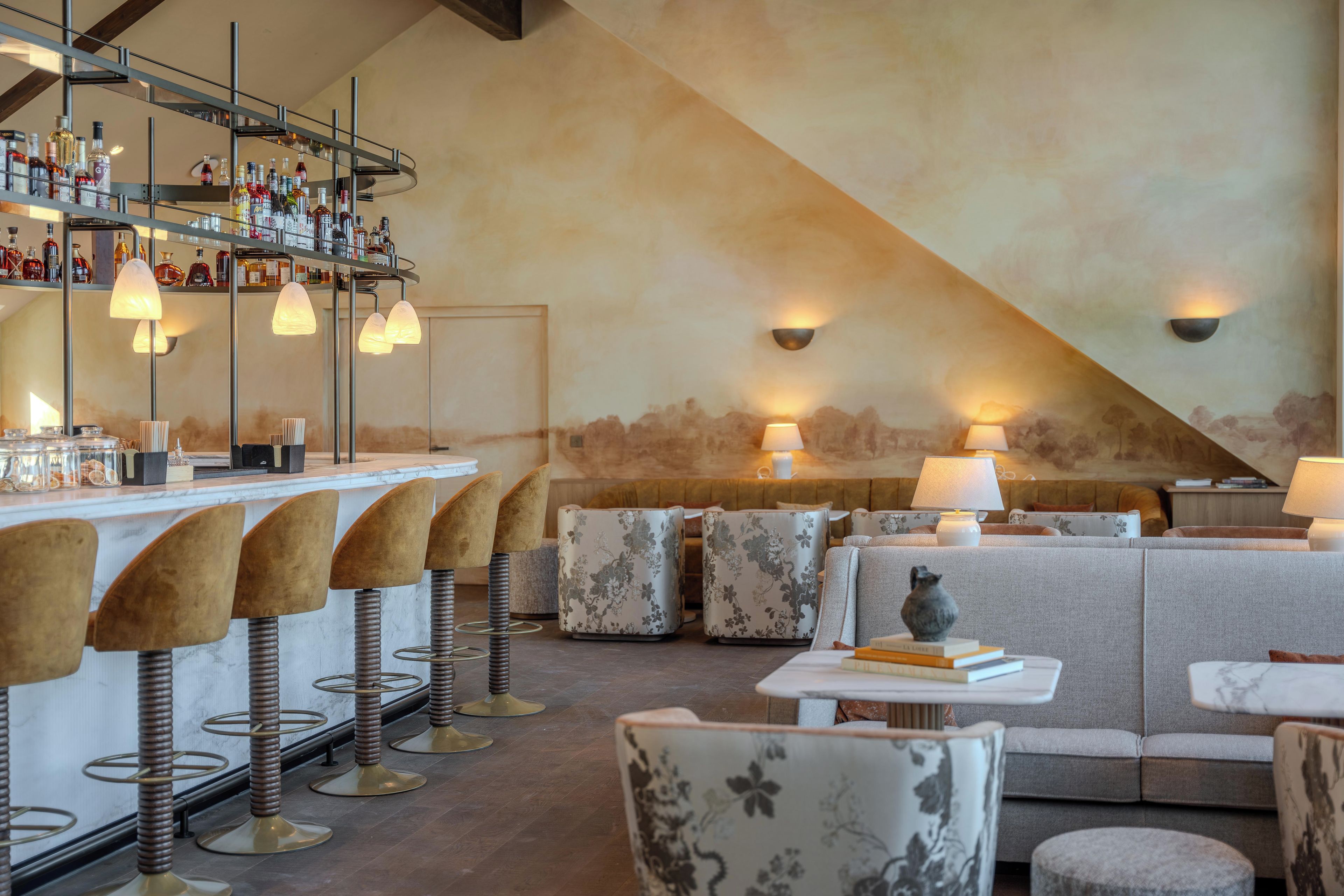A bar area with stools, a counter with bottles, and a seating area with sofas and tables.