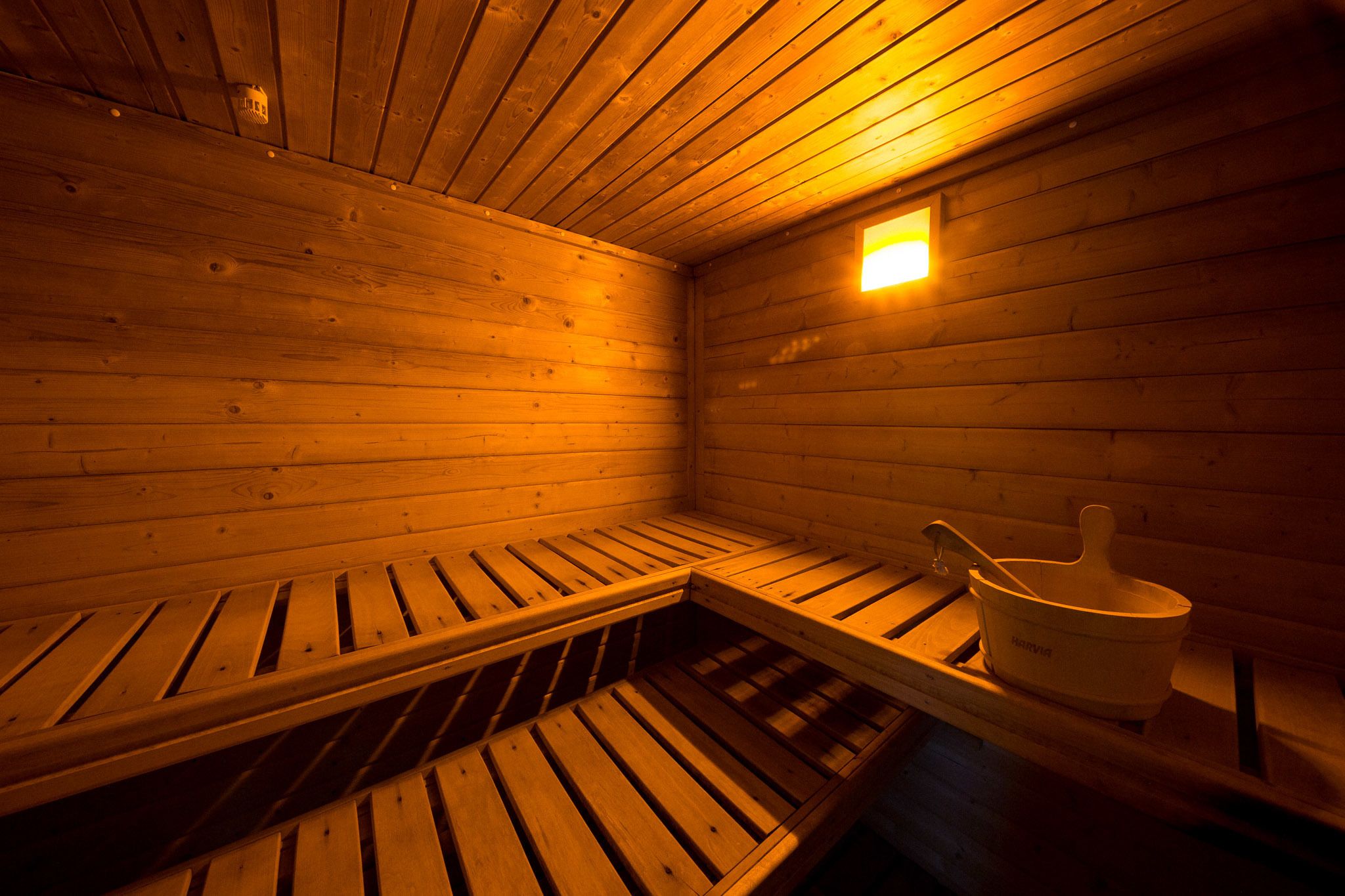 Un sauna avec des bancs en bois et un seau.