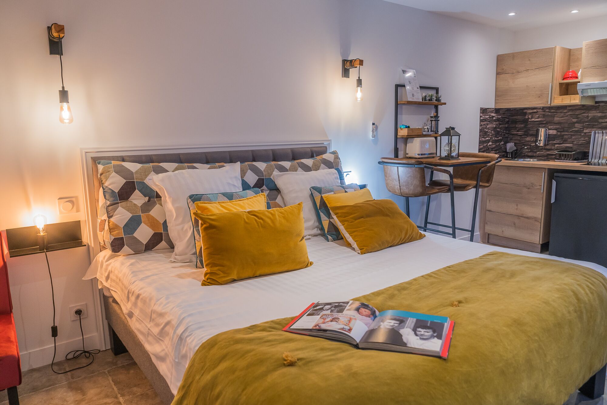 A modern bedroom with a bed, bedside lamps, a reading light, and a magazine on the bed.