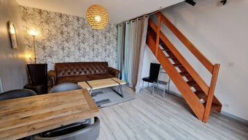 Una sala de estar moderna con un sofá de cuero marrón, una mesa de centro de madera y una escalera con barandillas de madera.