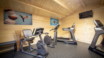 Una palestra con tapis roulant, cyclette e una panca.