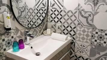 Une salle de bain avec un lavabo blanc, un miroir et une serviette.