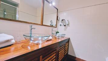 Un baño con dos lavamanos de vidrio, tocador de madera y un espejo grande.