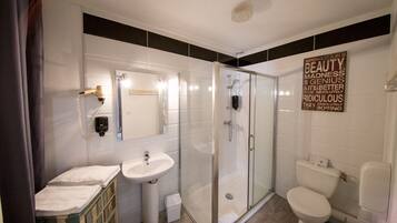 Un baño moderno con cabina de ducha de vidrio, lavamanos e inodoro.