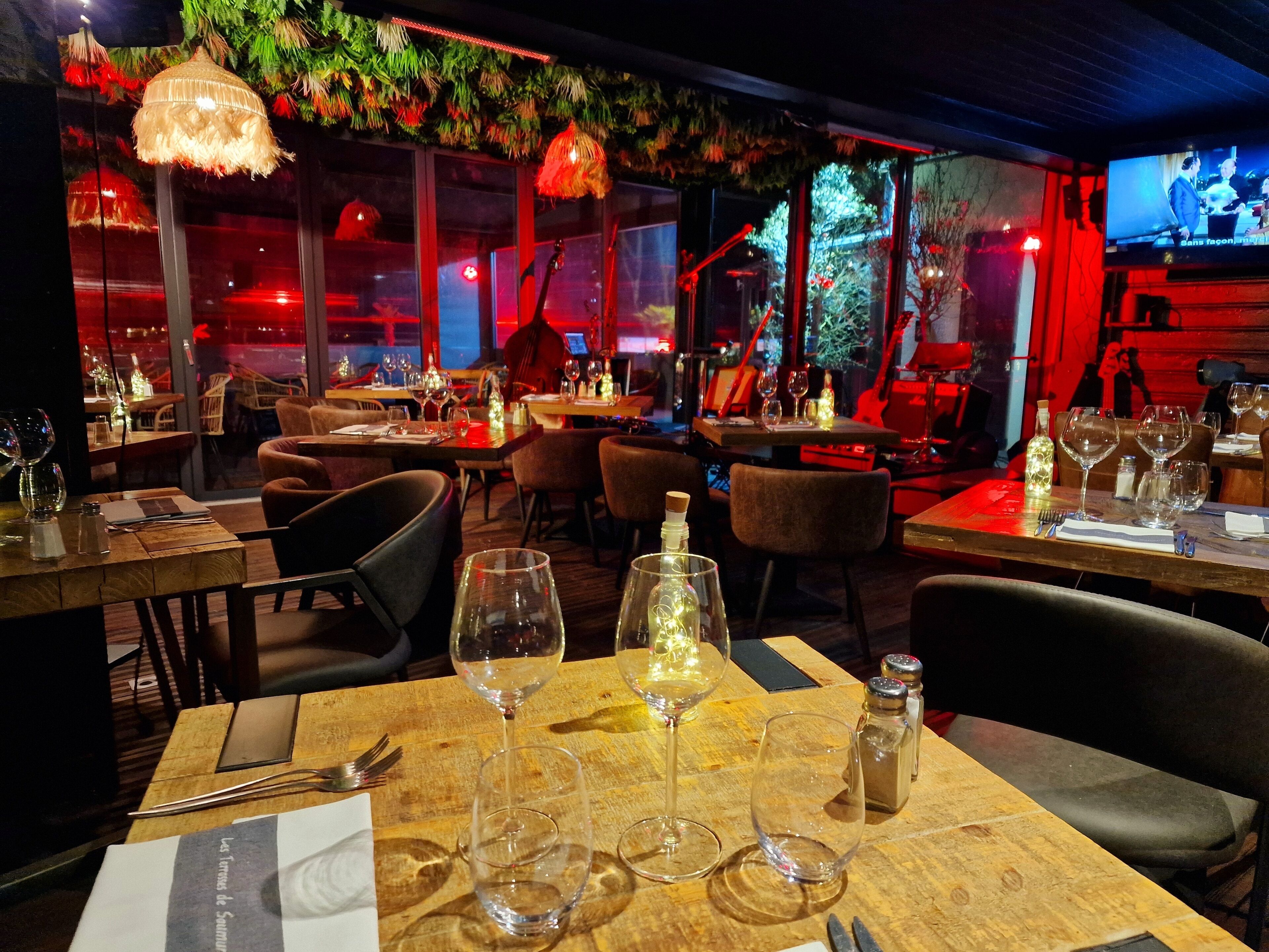 L'intérieur d'un restaurant avec des tables et des chaises en bois, ainsi que des luminaires suspendus.