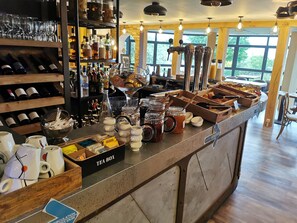 Zona de bar con estantes de botellas de vino, una caja de té y diversos condimentos.