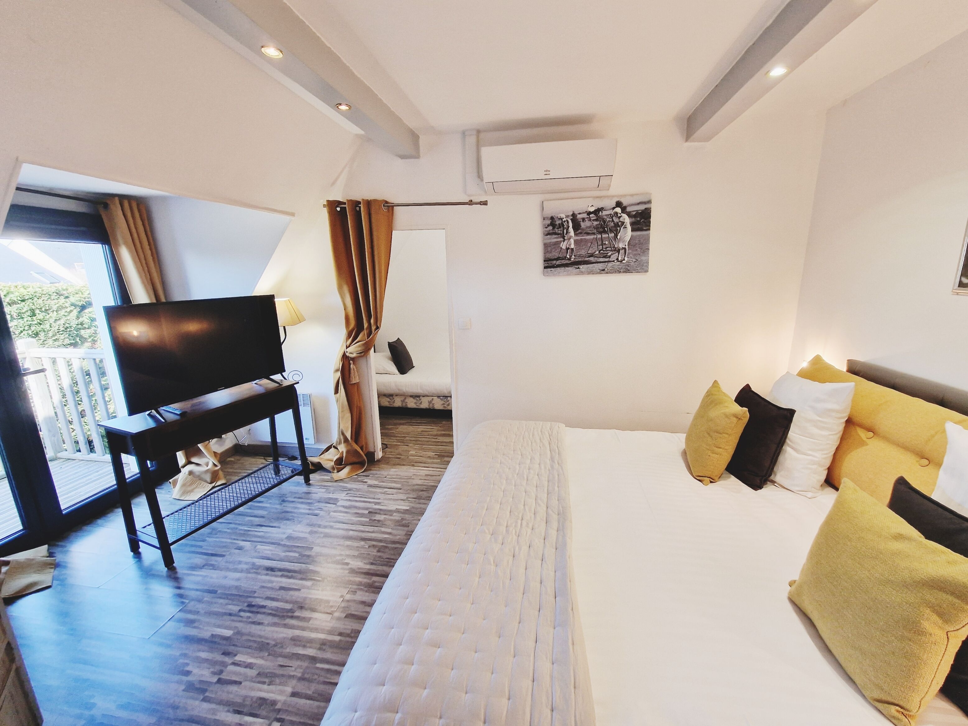 Un dormitorio con cama, televisor, escritorio y ventana.