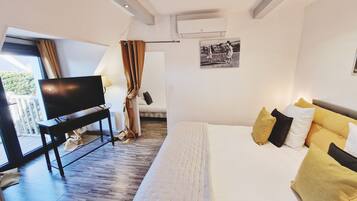 A bedroom with a bed, a TV, a desk, and a window.