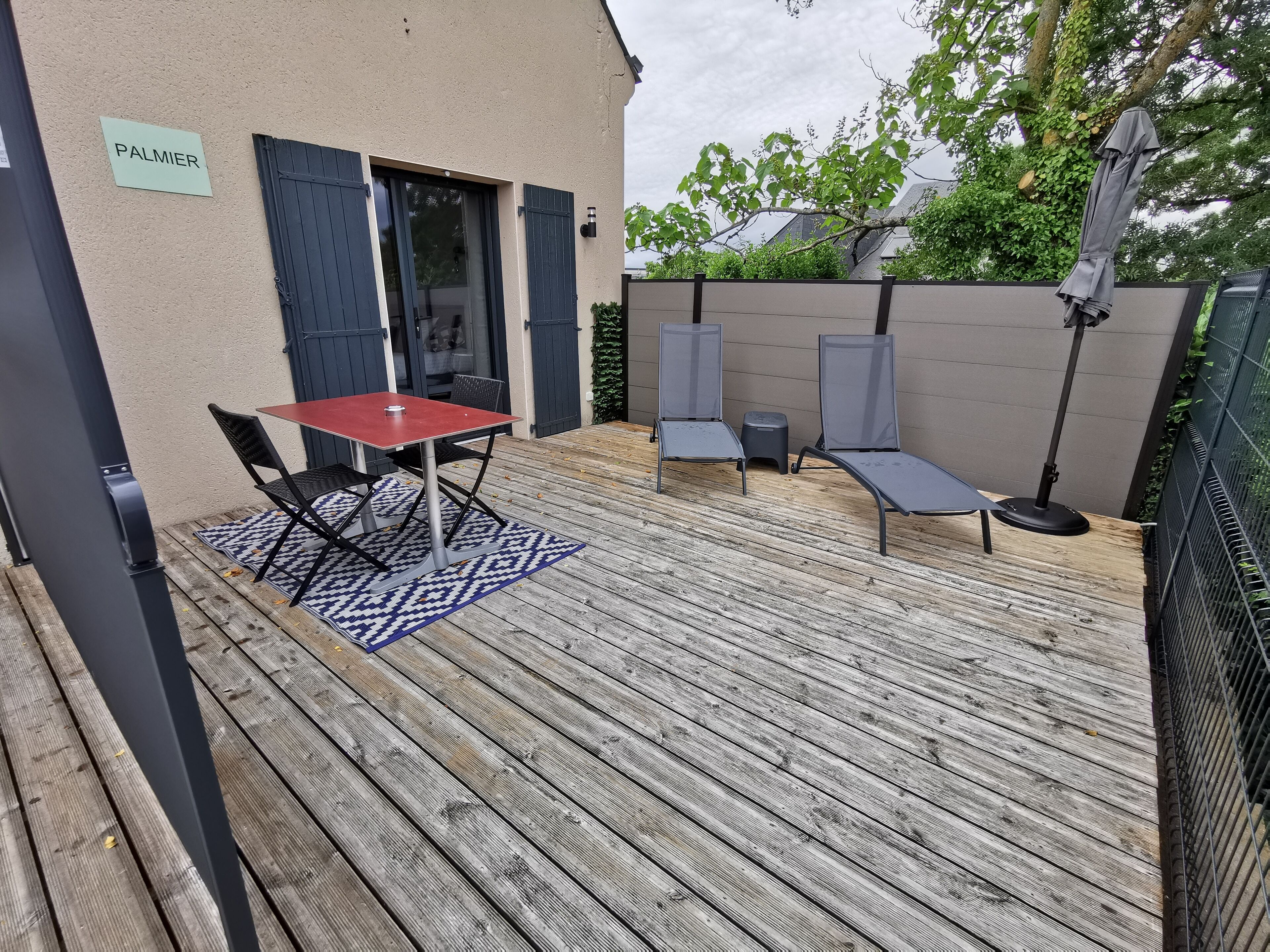 A patio with a table and chairs, a small stool, and a lounge chair.