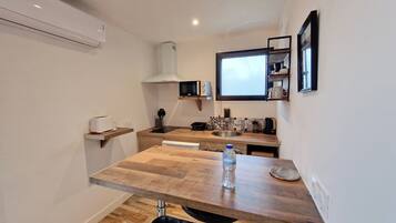 Una cocina compacta con una mesa de madera, un microondas y una botella de agua sobre la encimera.