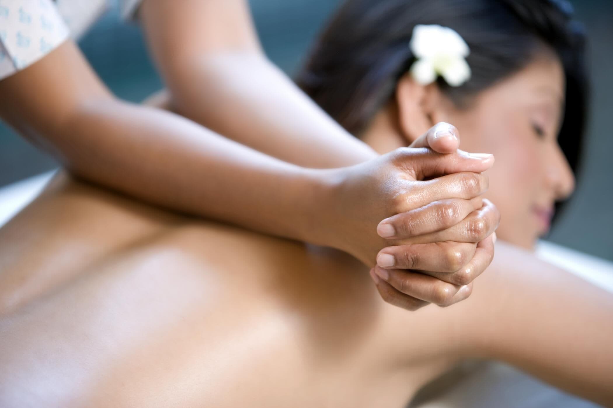 A close-up of hands holding another person's arm, suggesting a massage or physical therapy session.