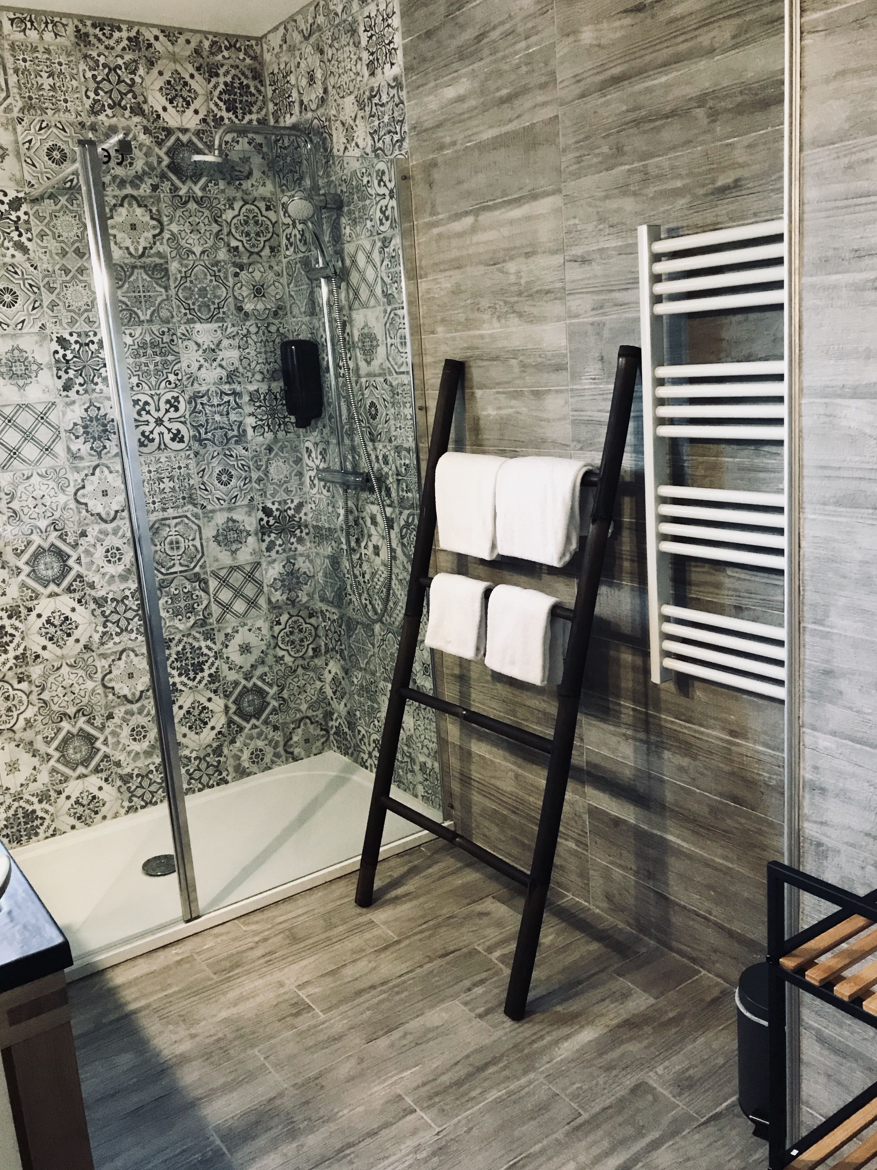 Un baño moderno con ducha, toallero y suelo de madera.
