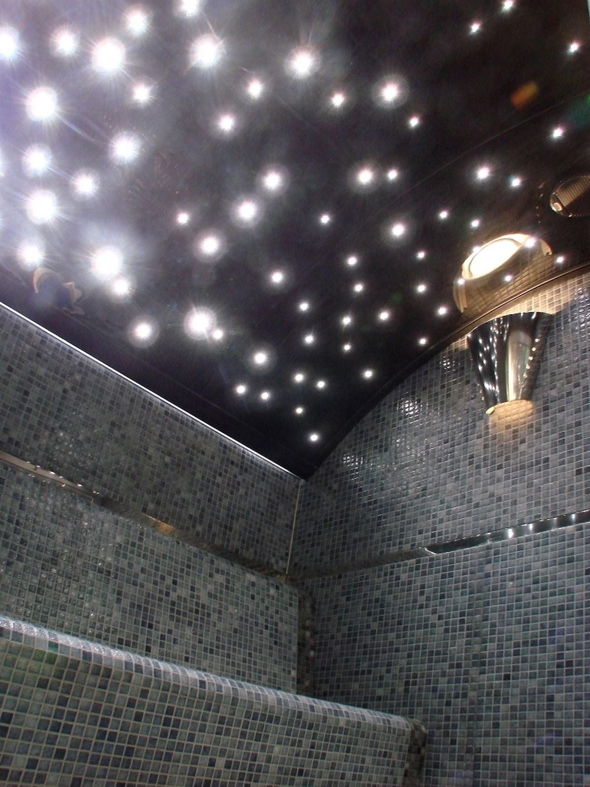 A tiled ceiling with numerous lights and a central fixture.