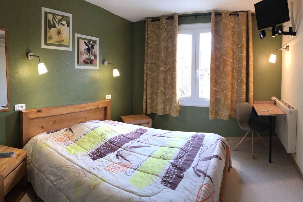 Ein Schlafzimmer mit einem Bett, einem Schreibtisch, einem Stuhl, einem Spiegel und zwei Wandleuchten.