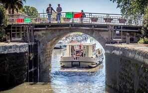 A stone bridge over a canal with a boat docked underneath. - Citotel Las Cigalas (Villeneuve-les-Beziers)