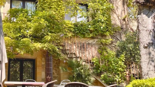 Un edificio de múltiples ventanales, paredes cubiertas de hiedra y fachada de piedra.