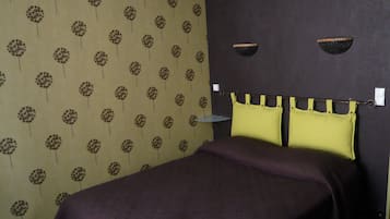 Ein Zimmer mit einem Bett, einem Kopfteil mit gelben Kissen und strukturiertem Wandpapier.