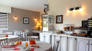 Un comedor con mesas, sillas, una estación de café y un refrigerador.