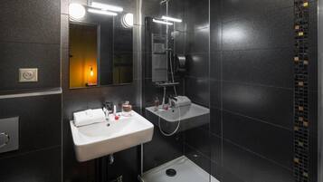 A modern bathroom with a white sink, a handheld showerhead, and a mirror.