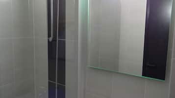 Un baño con cabina de ducha de vidrio, un lavabo blanco y un espejo.