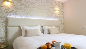 A neatly made bed with a tray of breakfast items including croissants, orange juice, and coffee.