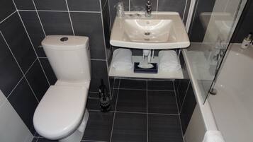 Ein modernes Badezimmer mit Toilette, Waschbecken und Duschkabine aus Glas.