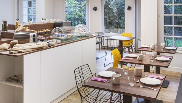Una cocina moderna con una isla central, ventanas amplias y un comedor con sillas amarillas.