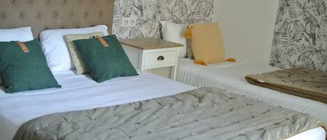 A hotel room with two beds, a nightstand, and a wall with a tropical leaf pattern.