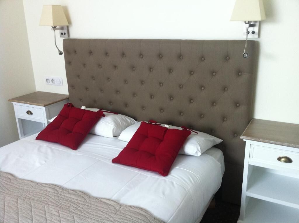 A neatly made bed with a tufted headboard, two bedside tables, and two wall-mounted lamps.