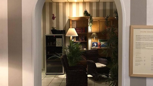 Een hal met betegelde vloer, een receptiebalie, een boekenkast en een bord met lijst aan de muur.