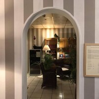 Un hall d’entrée avec un sol carrelé, un comptoir d’accueil, une bibliothèque et un panneau encadré accroché au mur.