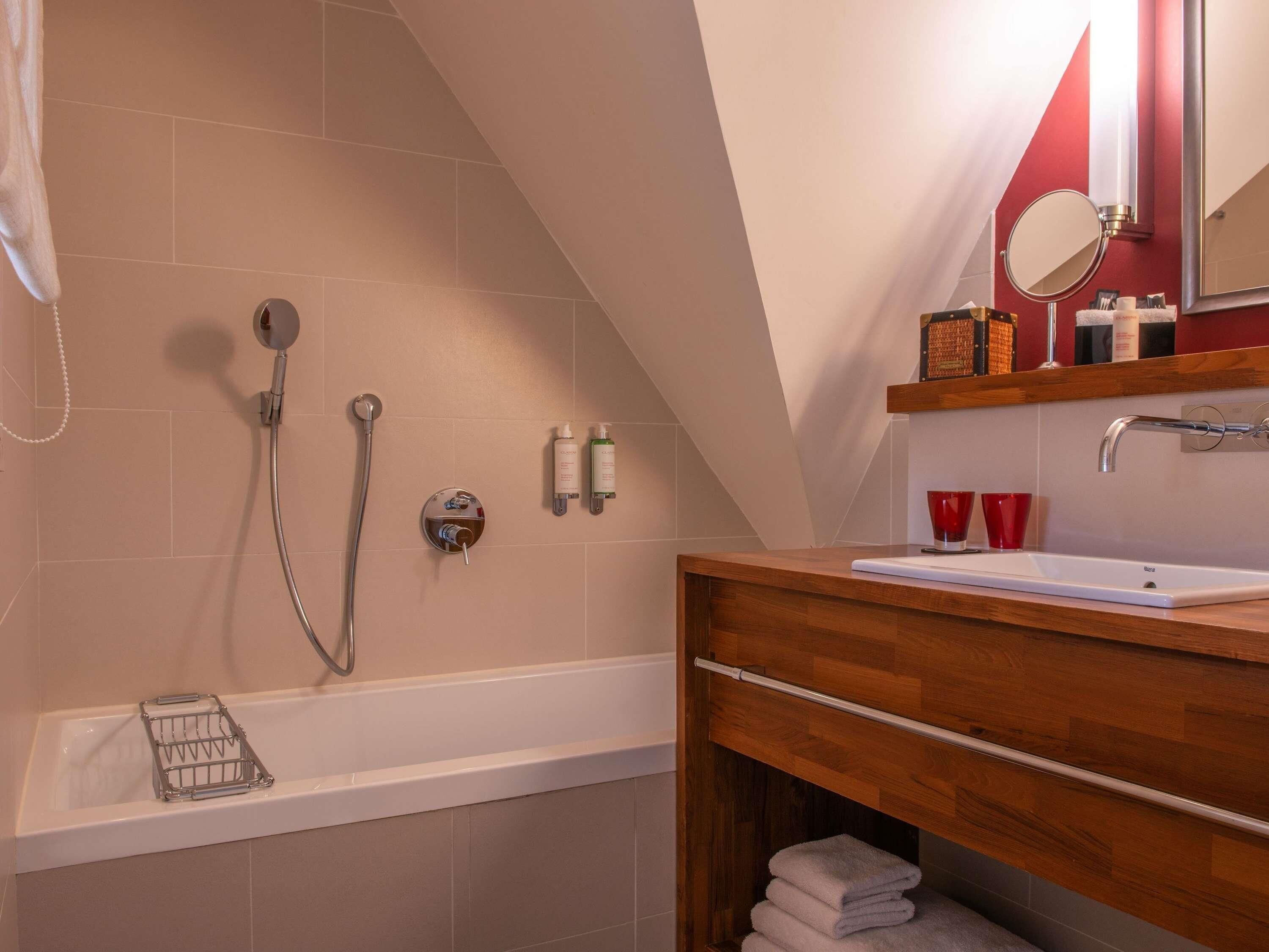 Ein modernes Badezimmer mit Badewanne, Dusche, Waschtisch und Spiegel.
