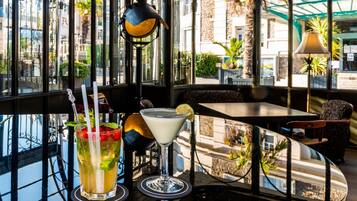 A table with two drinks, a glass with a lime wedge, and a martini glass with a lemon twist.