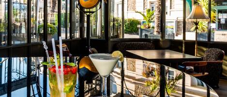 A table with two drinks, a glass with a lime wedge, and a martini glass with a lemon twist.