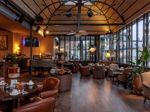 A cozy restaurant with a high ceiling, large windows, and a variety of seating options. - Royal Emeraude Hotel Dinard - MGallery Collection (Dinard)