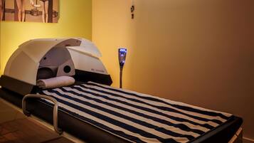 A treatment room with a massage table, a heating device, and a poster on the wall.