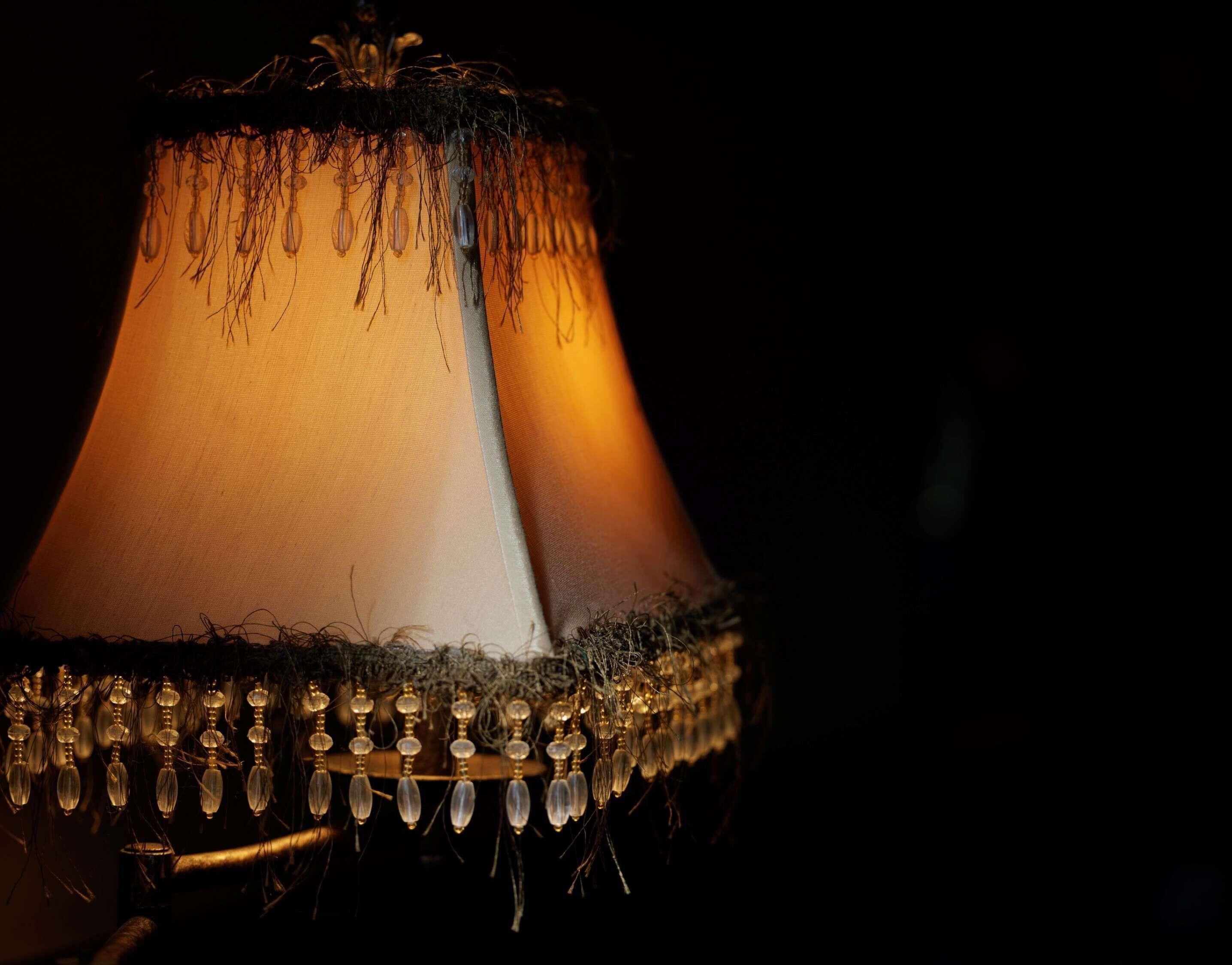 Um abajur com cúpula cônica e franjas decorativas.