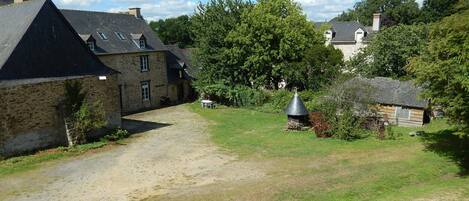 A stone building with a gravel driveway and a small garden area.
