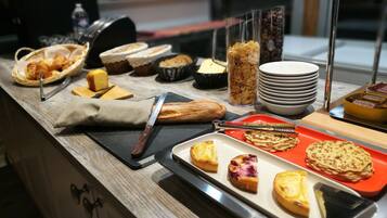 A breakfast buffet with various pastries, bread, and condiments.