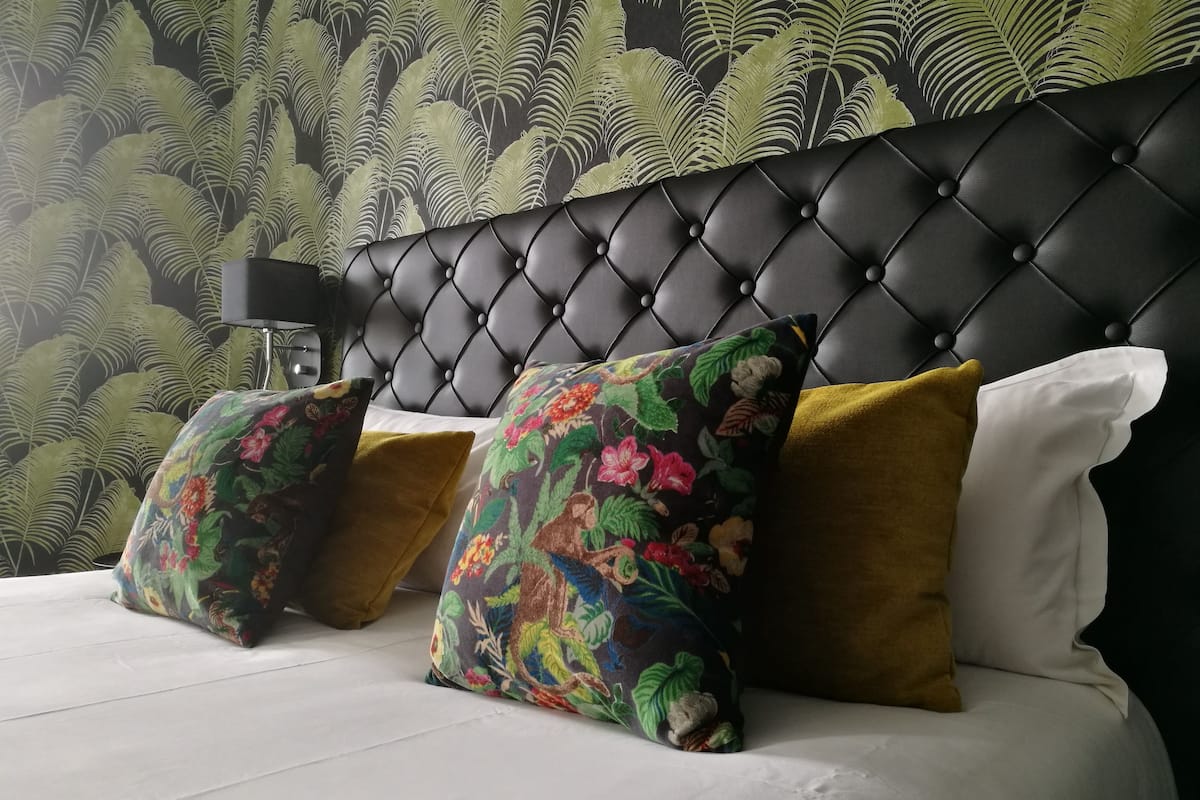 A bed with a tufted headboard, floral-patterned pillows, and a white bedspread.