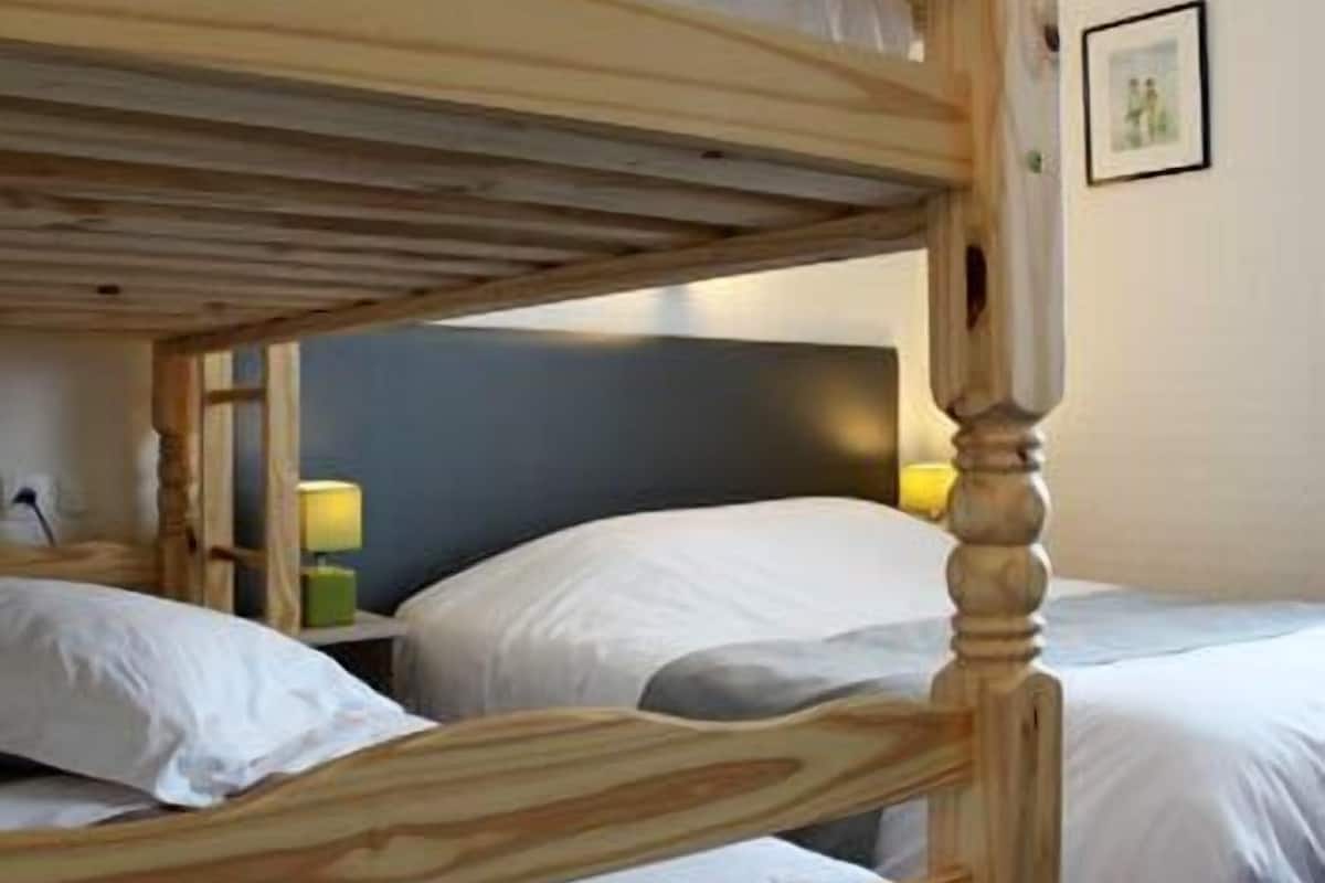 A bunk bed room with a wooden headboard, a bedside table with a lamp, and a framed picture on the wall.