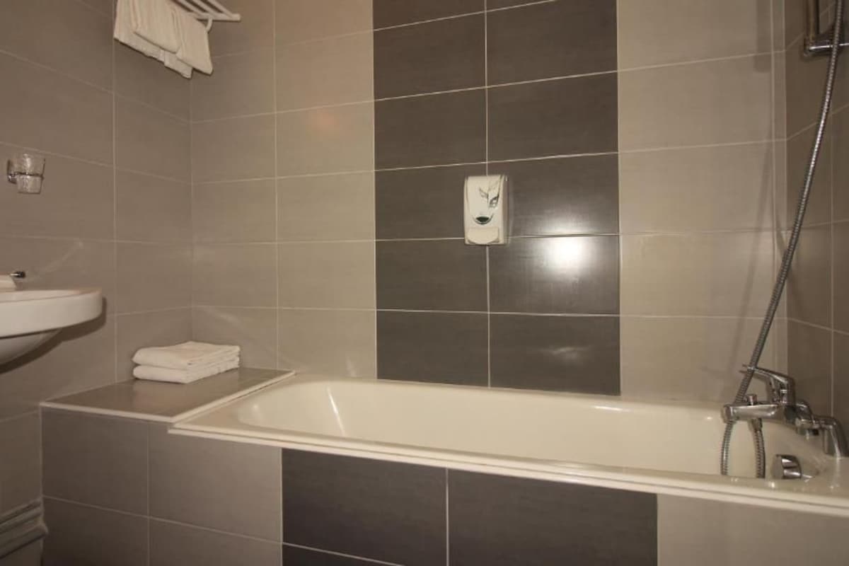 A bathroom with a sink, mirror, and a bathtub.