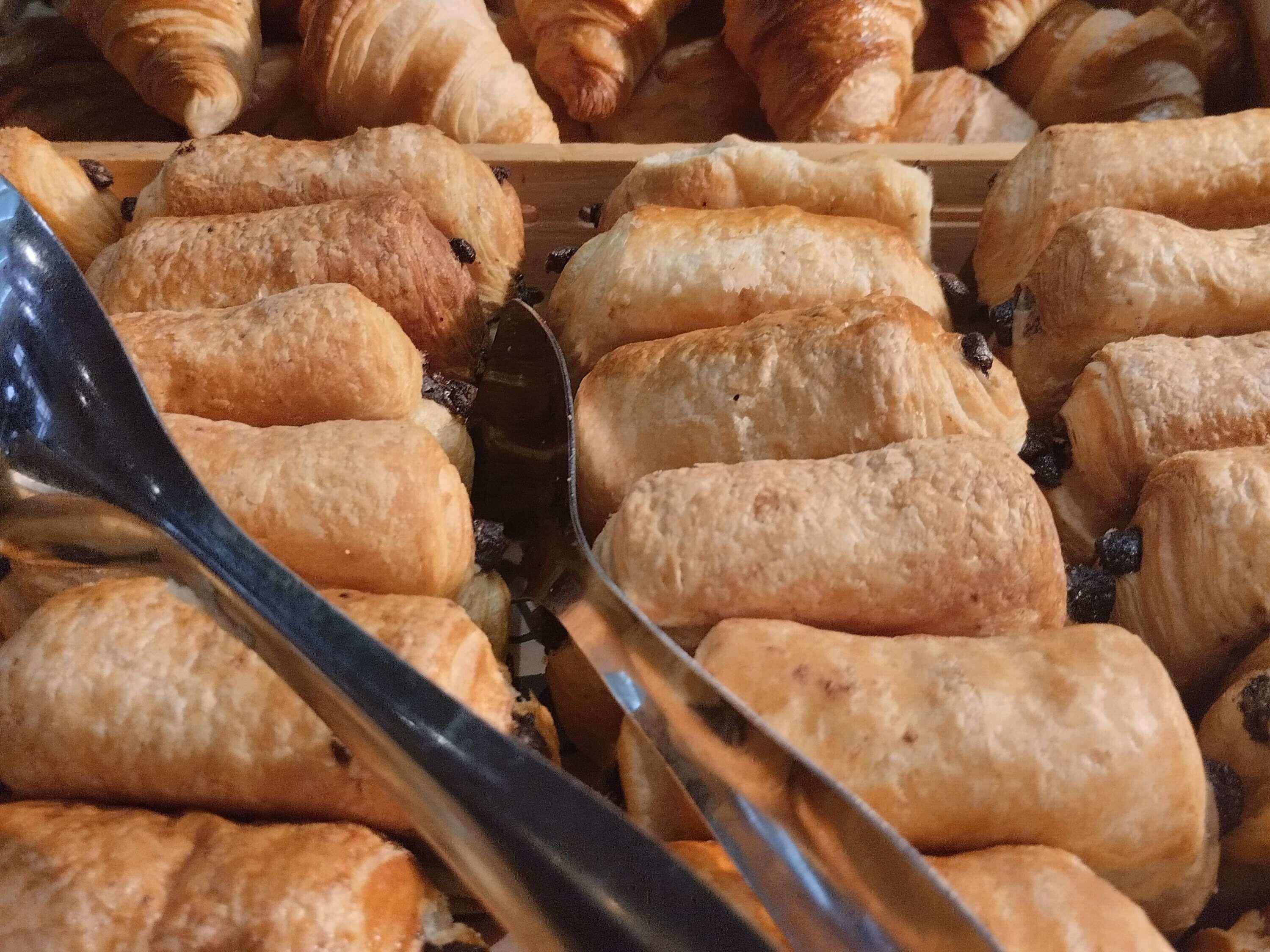 A variety of baked goods, including croissants and bread rolls, displayed in a bakery setting.