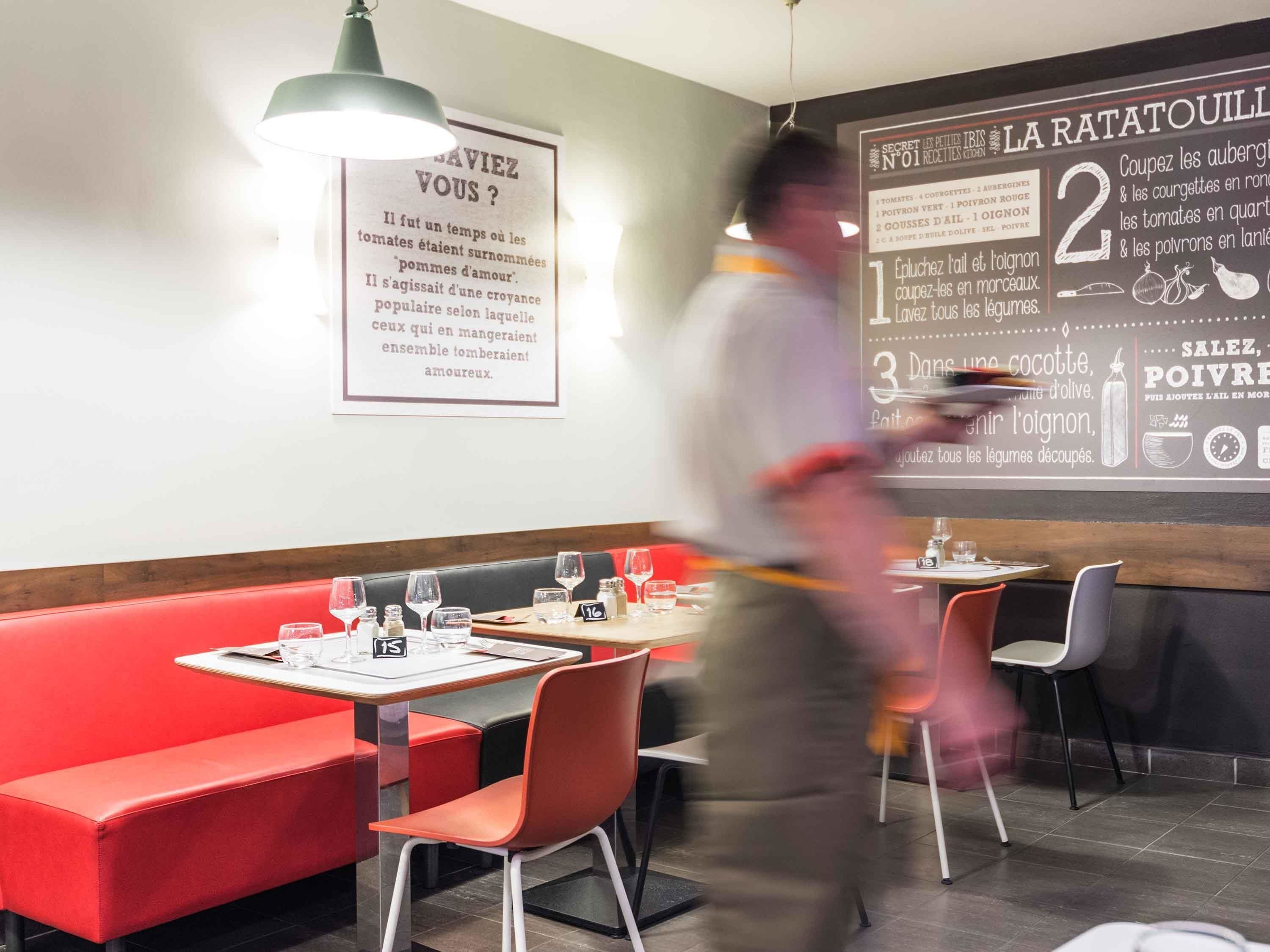 A restaurant interior with red booths, tables, and a chalkboard menu.
