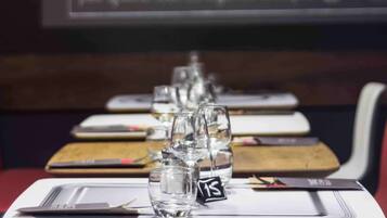 A dining table set with glasses and cutlery, with a menu board in the background.