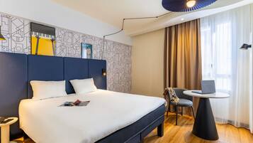 Una habitación de hotel moderna con una cama grande, una mesa redonda pequeña y una silla.