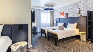 A hotel room with a bed, a desk, a chair, a TV, and a ceiling fan.