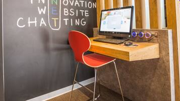 Un espace de travail comprenant un bureau, un ordinateur et une chaise rouge. Le mur est décoré de texte et de lambris en bois.